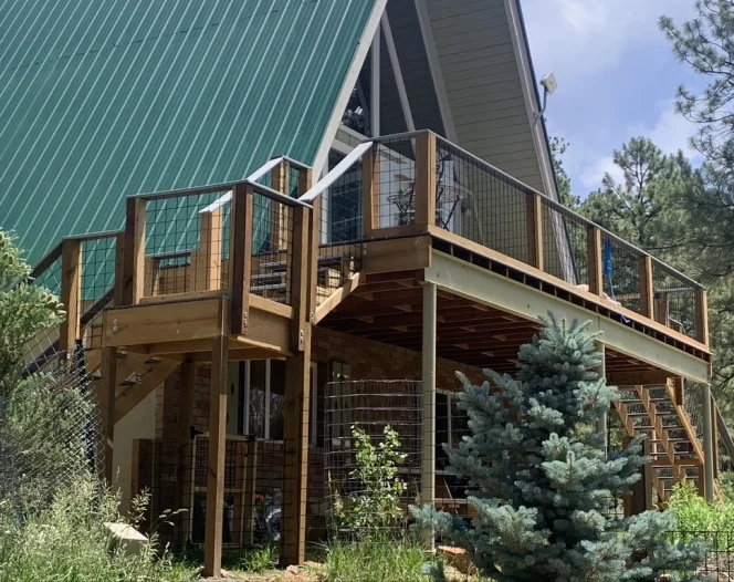 Custom elevated wood deck with wire railings attached to an A frame mountain home in Durango, Colorado. Outdoor living and scenic views